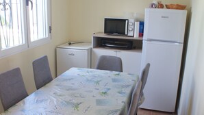 A small kitchen with a dining table, chairs, a microwave, a toaster, and a refrigerator. - Andalusian vacations (San Juan de los Terreros)