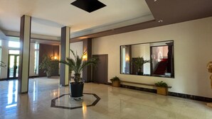 Eine geräumige Lobby mit hoher Decke, großen Fenstern und einer zentral platzierten Pflanze.