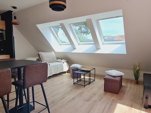 A modern loft bedroom with skylights, a dining area, and a small seating space. - New Studio 23m² Near Beach and Center All Inclusive (Saint-Brevin-les-Pins)
