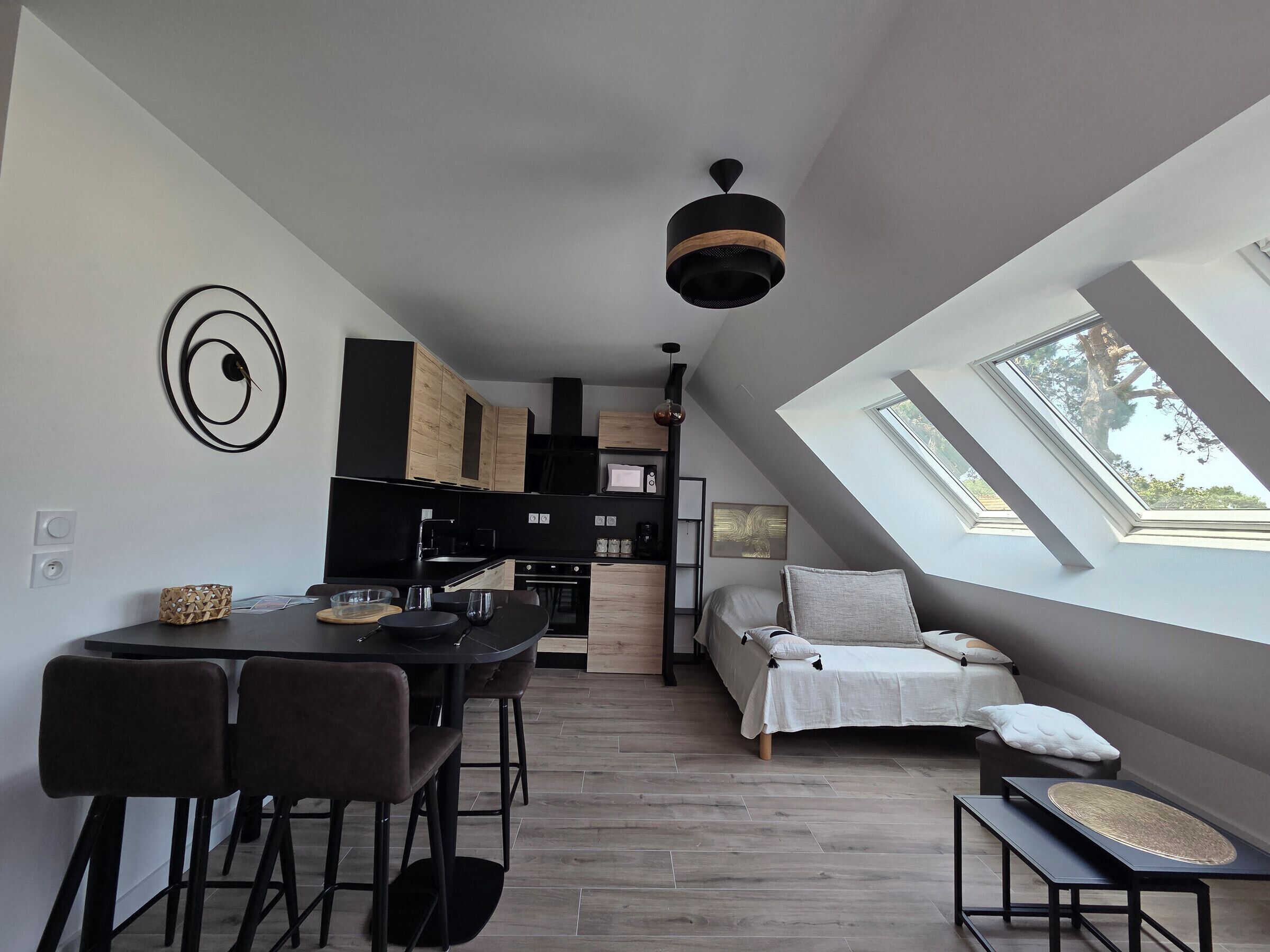 Un appartement moderne de style « loft » comprenant une cuisine, un coin repas et un espace nuit, avec des fenêtres de toit et un lit en mezzanine.