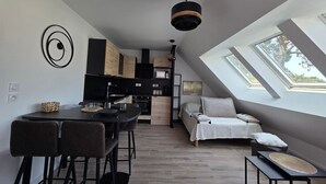 A modern loft apartment with a kitchen, dining area, and sleeping space, featuring skylights and a loft bed.