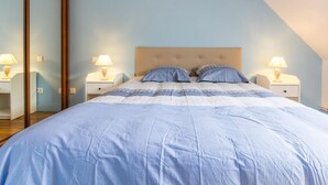 Quarto com cama, duas mesas de cabeceira e um espelho grande.