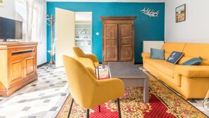 Uma sala de estar com um sofá amarelo, um armário de madeira e uma televisão.