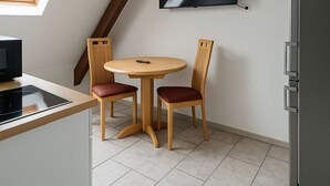 Une cuisine avec un coin repas, un téléviseur fixé au mur et un réfrigérateur.