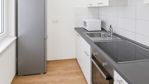 Eine Küche mit Kühlschrank, Mikrowelle, Spüle, Herd und Schränken.