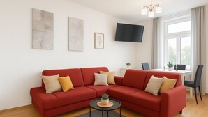 Ein modernes Wohnzimmer mit einem roten Sofa, einem kleinen runden Tisch und einem flachbildfernseher an der Wand.