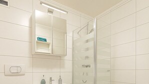 Et moderne badeværelse med toilet, håndvask, spejl og bruser.