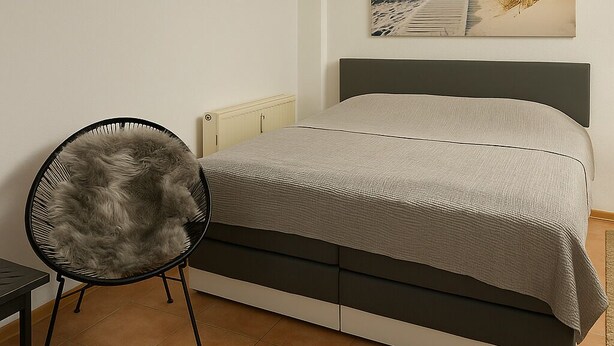 Une chambre à coucher avec un lit, une chaise, un tapis et un tableau accroché au mur.