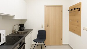 Une petite cuisine équipée d’une cuisinière, d’un évier et d’une chaise.