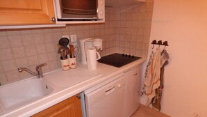 Una cocina compacta con fregadero, estufa y microondas.