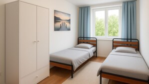 A bedroom with two single beds, a wardrobe, a window with curtains, and a painting on the wall. - Apartment Halle city center - 2 rooms (Halle (Saale))