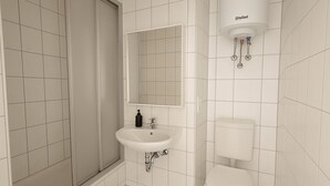 A bathroom with a shower, sink, toilet, and a mirror. - Apartment Halle city center - 2 rooms (Halle (Saale))