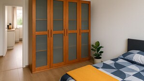Et soveværelse med en seng, et natbord, en potteplante og et garderobeskab med frostede glaslåger.