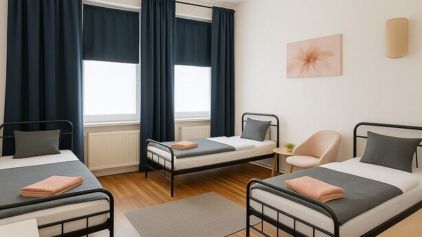 Une chambre avec deux lits, une chaise, un bureau et une fenêtre avec des rideaux.
