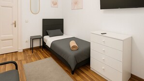 Une chambre à coucher avec un lit, une commode, une télévision et une porte.