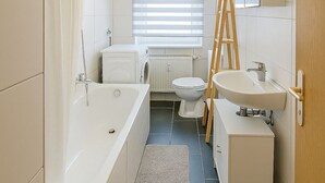 Et moderne badeværelse med badekar, toilet og håndvask.