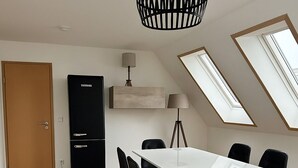 A modern kitchen with a white table, black chairs, and a black refrigerator. - House Delitzsch Holzstraße - 8 beds, parking lot (Delitzsch)