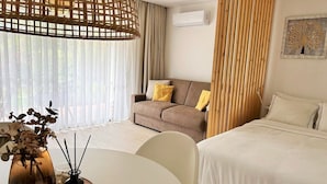 Une chambre d’hôtel moderne équipée d’un lit, d’un canapé, d’une table à manger et d’une plante décorative.