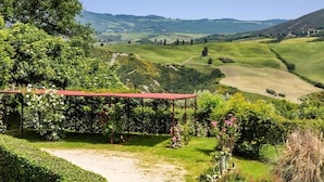 A lush garden with a red-roofed pergola, surrounded by greenery and flowers. - Luxury Podere Forncacchia - Privacy, Exclusive View (Toscana)