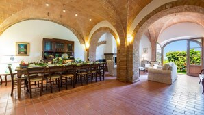 A spacious dining area with a brick ceiling and arches, a kitchen with wooden cabinets, and a view of greenery through a glass door. - Luxury Podere Forncacchia - Privacy, Exclusive View (Toscana)