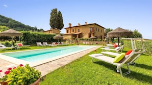 A pool area with lounge chairs, a swimming pool, and a large building in the background. - Luxury Podere Forncacchia - Privacy, Exclusive View (Toscana)