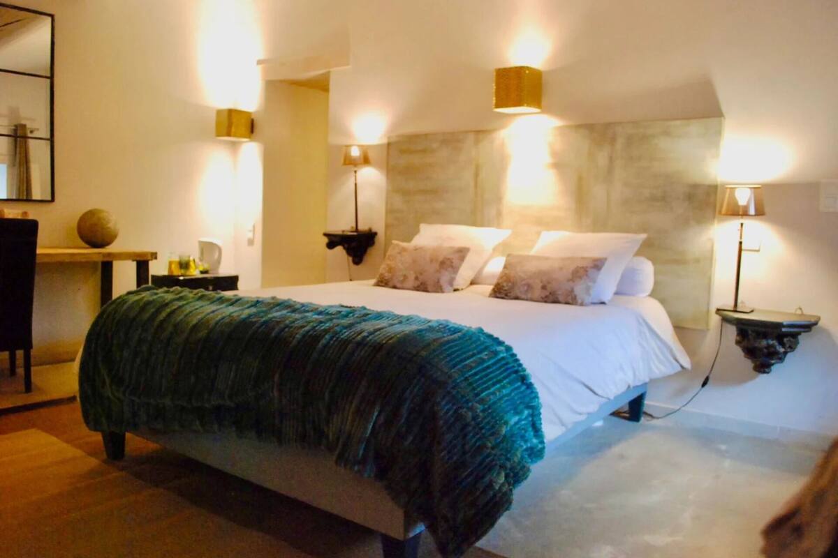 A bedroom with a bed, bedside tables, and wall-mounted lamps.