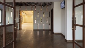 Una hall d'hotel moderna con pavimento in pietra lucidato, rivestimenti in legno e una ventola a soffitto.