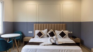 Una camera d'albergo con un letto, due poltrone, un tavolino e un comodino con il telefono.