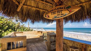 A wooden deck with a thatched roof, overlooking a beach. A sign reads "Steve & Laura's Tiki Hut, Est. 1987." - Welcome to “Salty Dog” - named after the old sea captain, this beautiful house directly on the Atlantic Ocean is decorated throughout with a nautical theme. With the breathtaking view of the ocean out your back door you will feel as though you are ac (Indialantic)