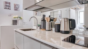 A modern kitchen with a stainless steel kettle, a coffee maker, and a sink.