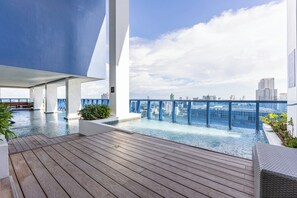 A rooftop infinity pool with a city view, wooden deck, and modern architecture. - 2 Furnished Studios with WiFi, Gym & Pool—Prime Central Location Cebu IT Park (Cebu City)