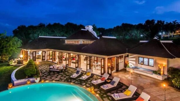 A large house with a swimming pool, outdoor seating, and a well-lit patio area. - Half Hill 1BR (Montego Bay)