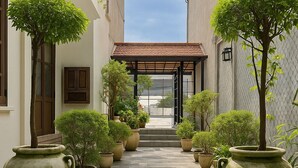 A corridor with potted plants and a tiled floor leading to a building entrance. - Colonial type 4-bedroom villa in Colombo with WiFi, AC (Colombo)