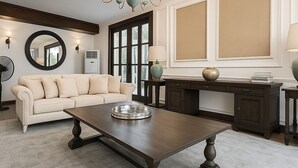 A living room with a dark wooden coffee table, a cream-colored sofa, a chandelier, and a large window with blinds. - Colonial type 4-bedroom villa in Colombo with WiFi, AC (Colombo)