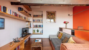 Een gezellige woonkamer met een bank, salontafel en boekenkasten vol boeken.