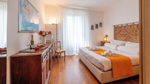 Een hotelkamer met een bed, een houten dressoir, een bureau met stoel, een kaart aan de muur en een raam met gordijnen.
