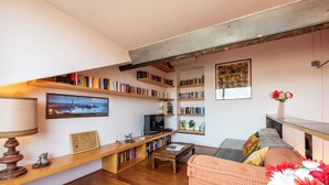 Een gezellige woonkamer met een houten salontafel, een bank en boekenplanken vol boeken.