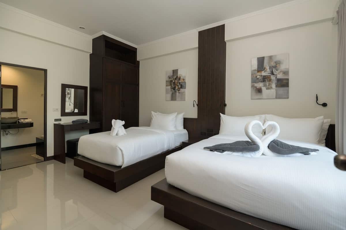 A hotel room with two beds, a bathroom, and artwork on the walls.