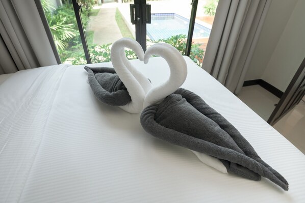 Un lit décoré avec des serviettes disposées en forme de cœur.