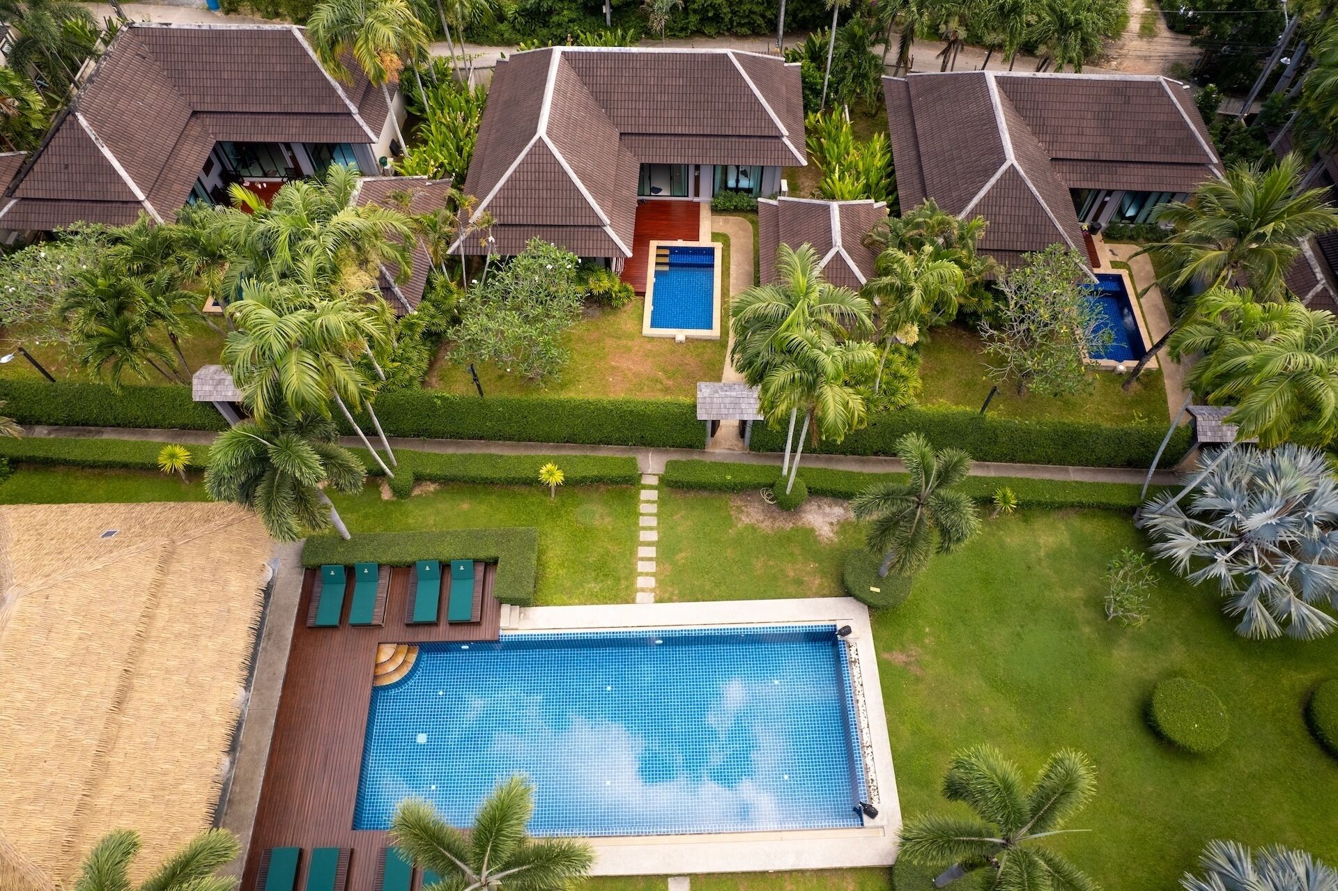 Un complexe hôtelier comprenant plusieurs villas, une piscine centrale et des jardins bien entretenus.