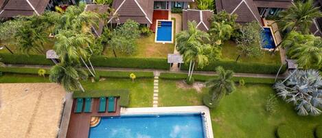 Un complexe hôtelier comprenant plusieurs villas, une piscine centrale et des jardins bien entretenus.