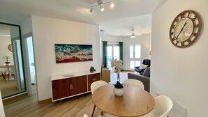 Uma sala de estar moderna com área de jantar, um quadro grande e um relógio na parede.