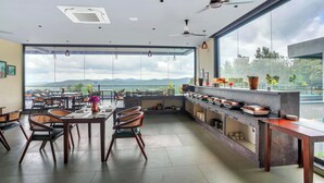 Un vaste espace de salle à manger avec vue sur les montagnes, un comptoir de cuisine et des ventilateurs de plafond.