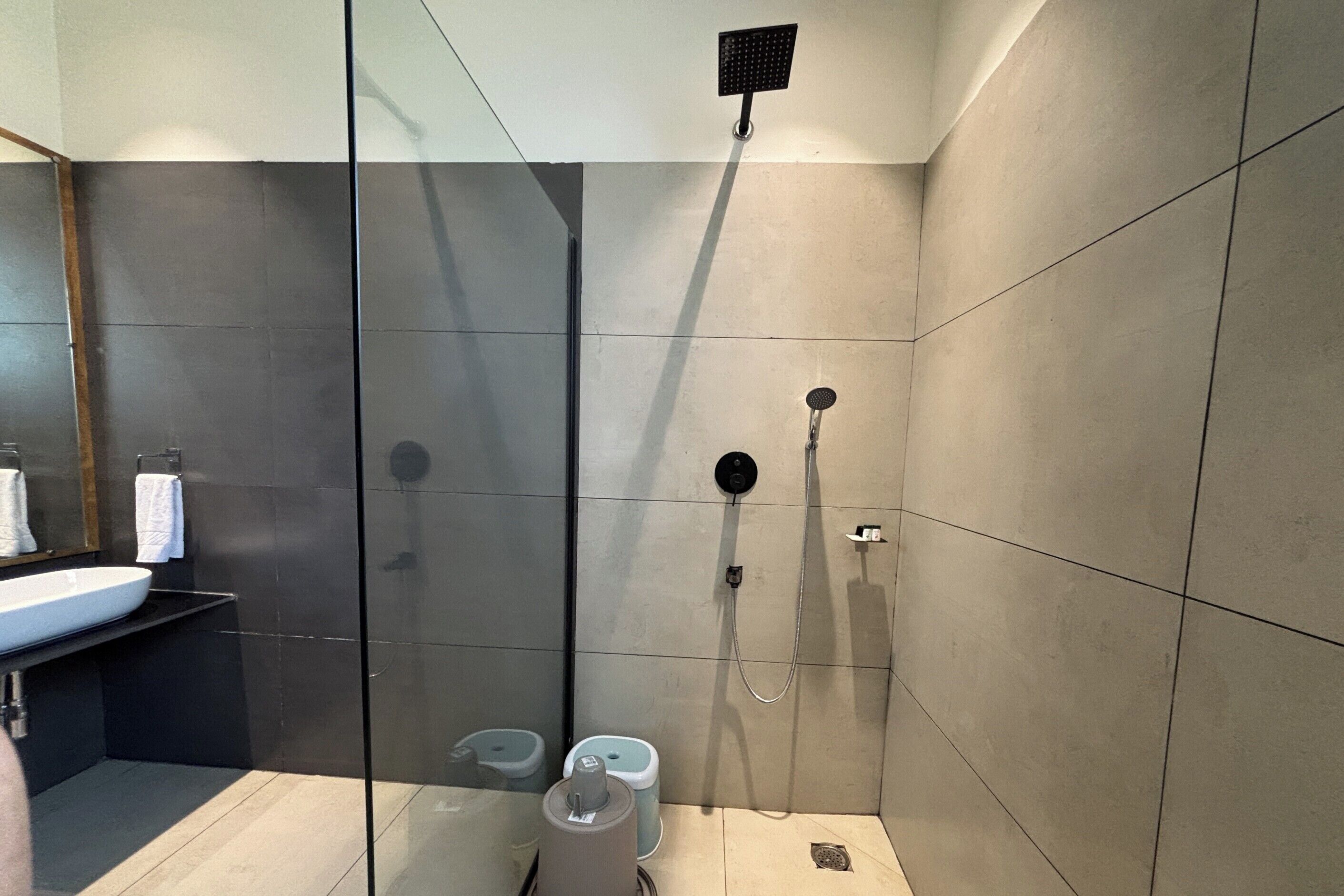 A modern bathroom with a glass-enclosed shower, a sink, and two toilets.