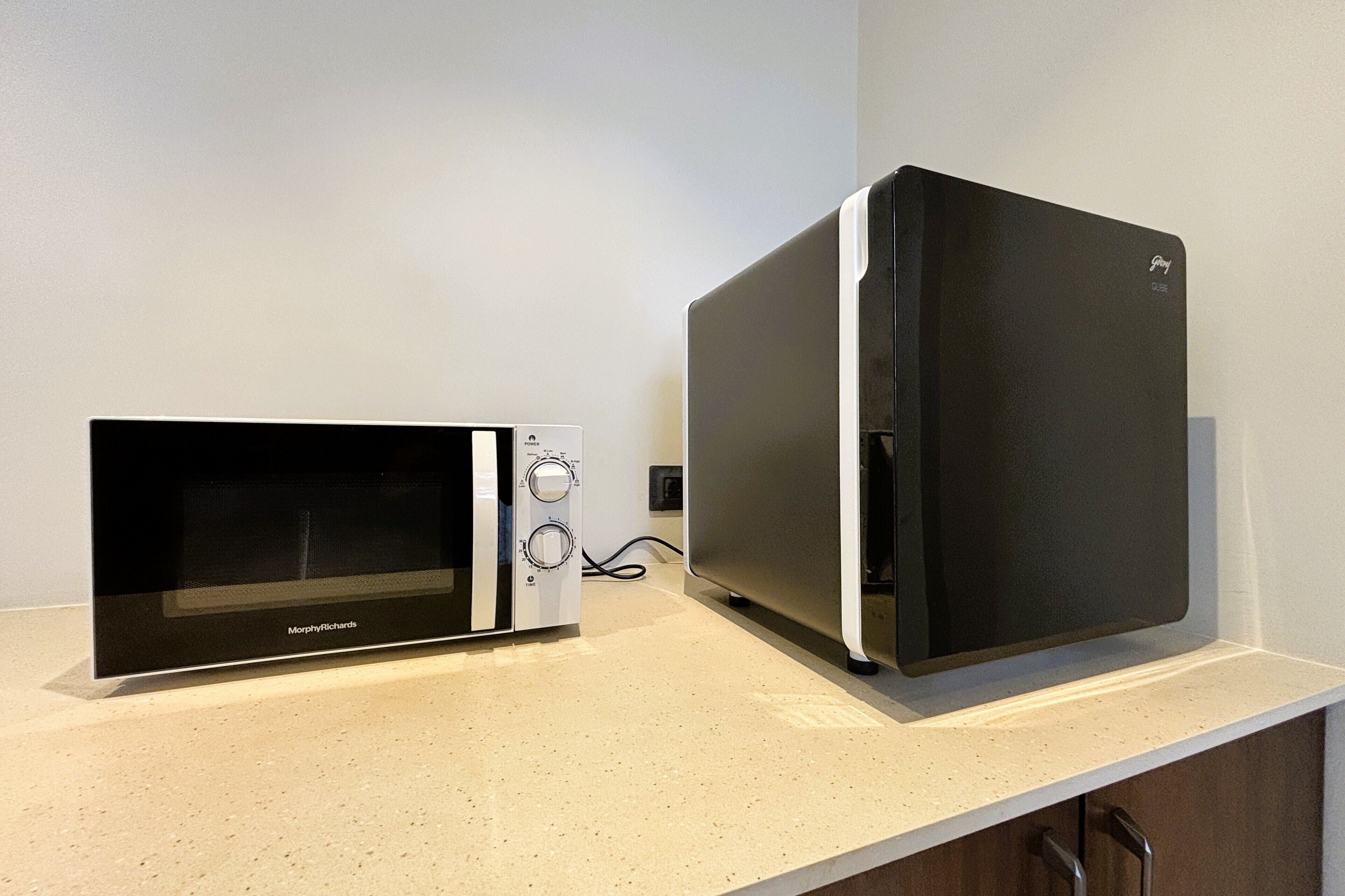 A kitchen with a black microwave and a black refrigerator on a countertop.