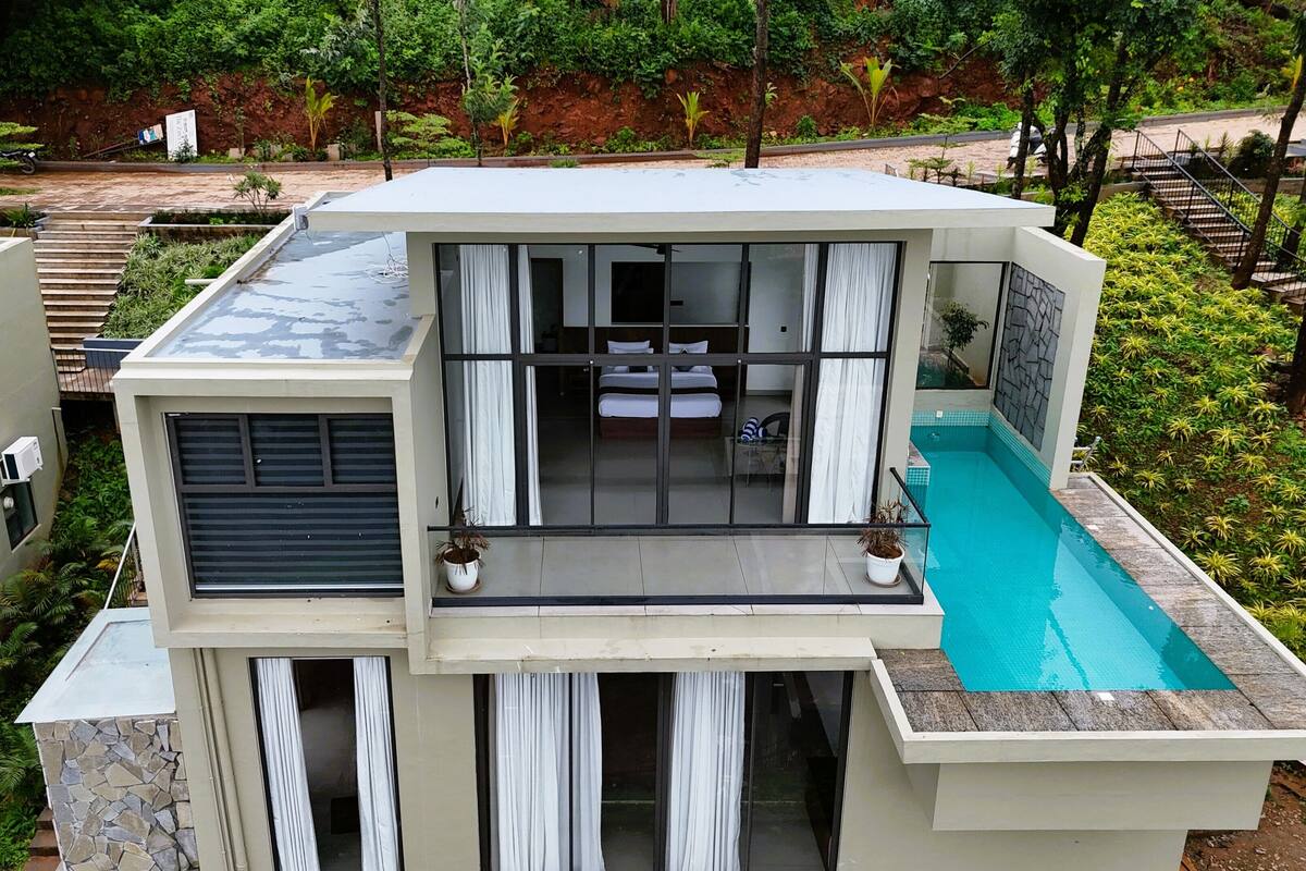 A modern building with a pool, large windows, and a balcony.
