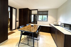 Eine moderne Küche mit Marmorarbeitsplatte, dunklen Holzschränken und einer eingebauten Mikrowelle.