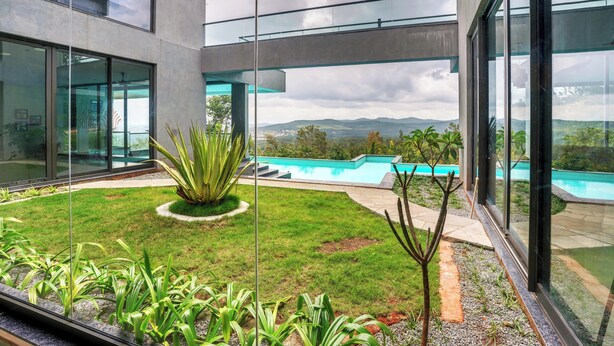 Un bâtiment moderne doté de grandes fenêtres en verre, d’une piscine et d’un jardin bien entretenu.