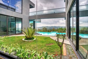 A modern building with large glass windows, a swimming pool, and a well-maintained garden. - Sila Secret Mirage (Mudigere)