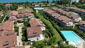 Un barrio residencial con varias casas de dos pisos, una piscina y vistas a una gran masa de agua.